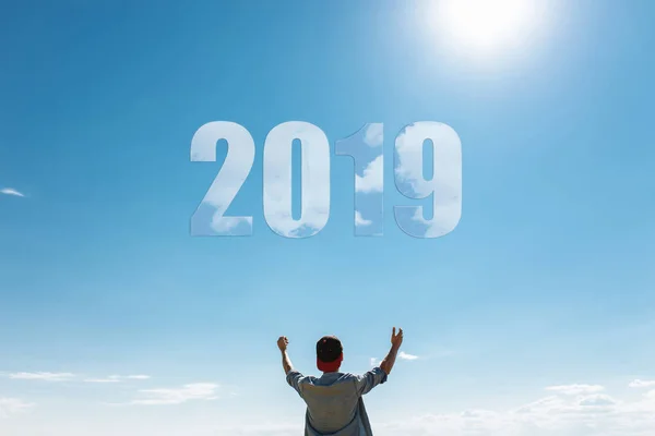 Man, against the blue sky, the guy pulls hands to the sky, the concept of the new 2019 year. Christmas