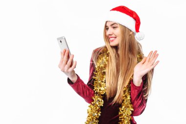 Noel Baba ve elbise, şapkalı güzel kız ellerini ve, gözü üstünde bir akıllı telefon ile selamlar gönderir. Beyaz bir arka plan üzerinde