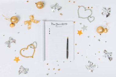 boş boş defter. Beyaz zemin üzerine altın Noel süsler. Rahat bir ortamda yeni yıl planlama.