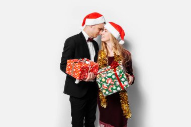 Sevgili, Noel Baba şapkaları, mutlu bir çift yeni yıl Noel hediyeleri ellerinde ile kutluyor. Beyaz bir arka plan üzerinde.