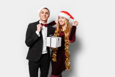 Sevgili, Noel Baba şapkaları, mutlu bir çift yeni yıl Noel hediyeleri ellerinde ile kutluyor. Beyaz bir arka plan üzerinde.