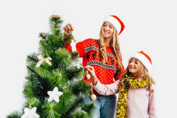 ママと娘 サンタ クロースの帽子をかぶって クリスマス ツリーを飾る一緒に 白い背景の上 ロイヤリティフリーのストック画像