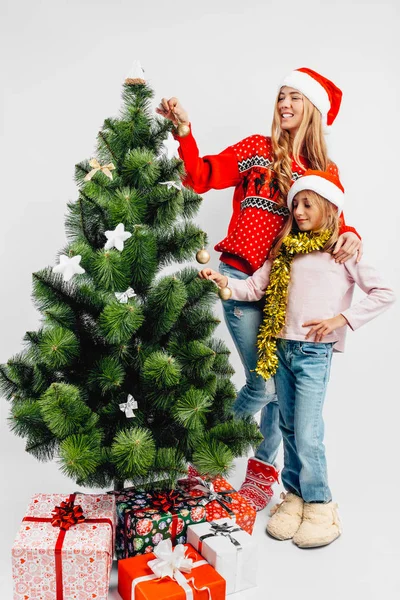 Mutter Und Tochter Schmücken Mit Weihnachtsmann Hüten Gemeinsam Den Weihnachtsbaum Stockbild