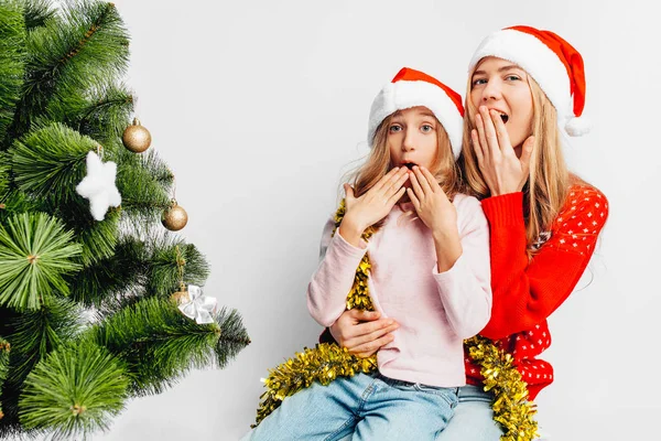 Schockierte Mutter Und Tochter Weihnachtsmützen Weihnachtsbaum Sitzend Das Neue Jahr lizenzfreie Stockfotos