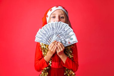 Genç kız, Noel Baba'nın şapkalı ve tinsel boynunda kırmızı bir arka plan üzerinde izole onun elinde dolarla ile. Noel, gelirleri için iş kavramı