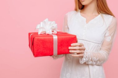 bir beyaz kız elbise kırmızı hediye kutusu ile elinde, pembe bir arka plan