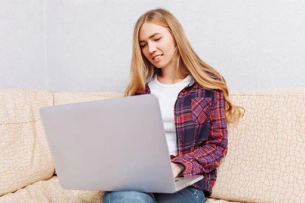 girl with laptop chatting, sitting on sofa at home, concept of communication and technology.