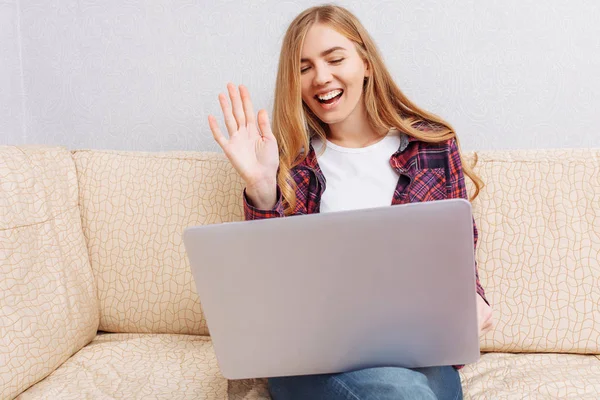 Piękna Dziewczyna Siedzi Kanapie Domu Laptopem Rozmowy Wideo Pozdrawia — Zdjęcie stockowe
