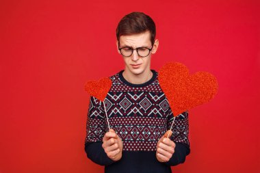 Sopa üzerinde kırmızı bir arka plan, Sevgililer günü kırmızı kalpler gözlüklü bir adam