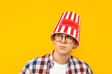 Neşeli adam gözlük ile bir kova patlamış mısır kafasına sarı bir arka plan üzerinde bir film izlemek mutludur