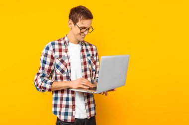 sarı bir arka plan üzerinde bir dizüstü bilgisayar ile gözlüklü adam adam online alışveriş yapıyor