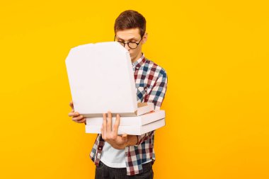 bir adam bir kutu pizza sarı bir arka plan üzerinde tutar, bir pizza kutusu bakan bir adam