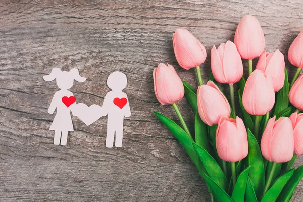 女孩和男孩被剪掉了纸 一对有爱心的夫妇在木制背景下 在一束粉色郁金香的背景下 情人节 — 图库照片