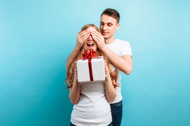 Yakışıklı bir adam ona bir sürpriz yapma onun kadın gözleri kapanır ve onu mavi bir arka plan karşı bir hediye verir. Sevgililer günü