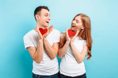 Sevgi, erkek ve kadın, güzel çift giymiş beyaz t-shirt, kağıttan, açık mavi renkli kırmızı kalpler ile poz içinde. Sevgililer günü