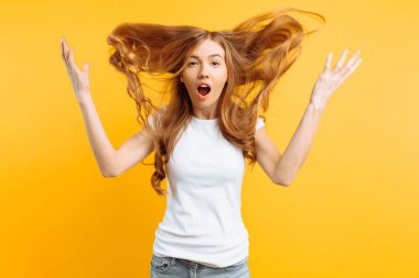 Genç kız beyaz tişört, sarı bir arka plan üzerinde iyi haber tarafından şok şok