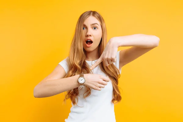 Piękna Dziewczyna Patrząc Zegarek Ręka Wskazuje Zegarek Żółtym Tle Pojęcie — Zdjęcie stockowe