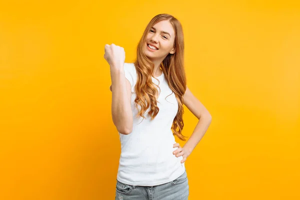 Porträt eines glücklichen Mädchens, das mit erhobenen Fäusten den Sieg auf gelbem Hintergrund feiert. das Konzept der Leistung. — Stockfoto