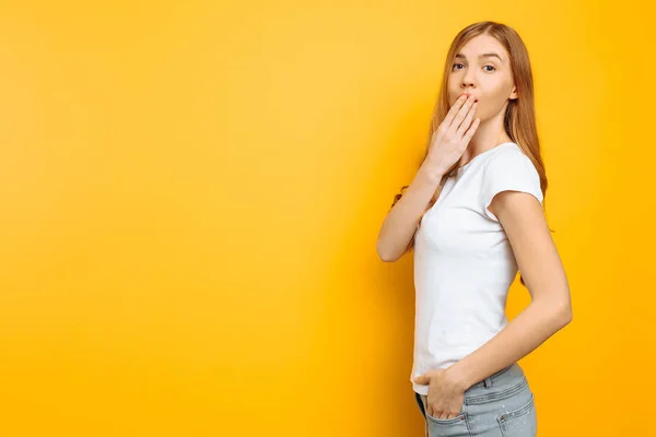 Retrato de una chica sorprendida, apuntando a un espacio vacío sobre un fondo vacío, sobre un fondo amarillo — Foto de Stock