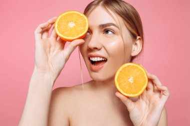 Neşeli bir kadınsı kız, doğal açık cilt, bir portakal, bir gözün kapsayan bir kız portakal, iki adet portre bir pembe izole. Cilt bakım kavramı, doğal güzellik