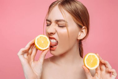 Bir neşeli kadınsı kız, doğal açık cilt, pembe bir arka plan üzerinde izole iki limon dilimleri ile kız portresi. Cilt bakım kavramı, doğal güzellik