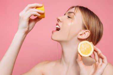 Bir neşeli kadınsı kız, doğal açık cilt, pembe bir arka plan üzerinde izole iki limon dilimleri ile kız portresi. Cilt bakım kavramı, doğal güzellik