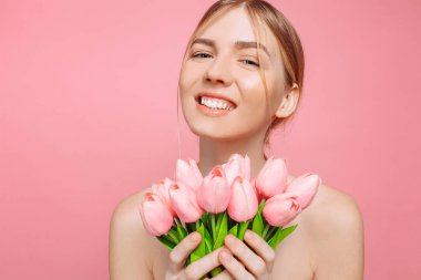 Güzel genç kız ile temiz cilt tutan bir buket pembe t
