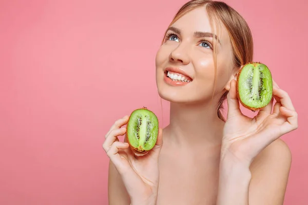 Aantrekkelijk meisje kiwi segmenten, te houden op een roze achtergrond. Natur — Stockfoto