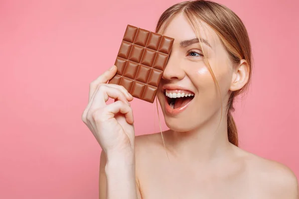 Jonge vrouw met schone huid een zwarte balk van chocolade in bedrijf — Stockfoto