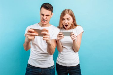Genç çift ayakta, cep telefonlarında oyun heyecanlı, 