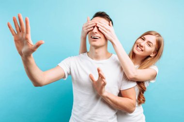 sevgi dolu bir çift, bir kadın ve bir erkek bir kadın kapanır bir adam gözler giyinmiş, mavi bir arka plan üzerinde bir sürpriz yapmak istiyor