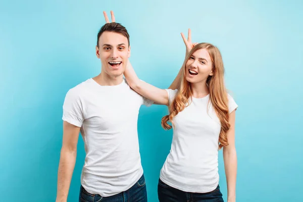 A cheerful young couple, a man and a woman , set horns to each o — Stock Photo, Image