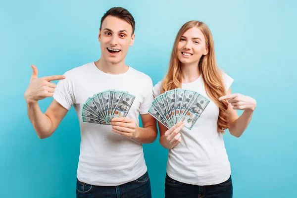 Foto di una giovane coppia felice innamorata, uomo e donna, vestita con denaro in mano, su uno sfondo blu — Foto Stock