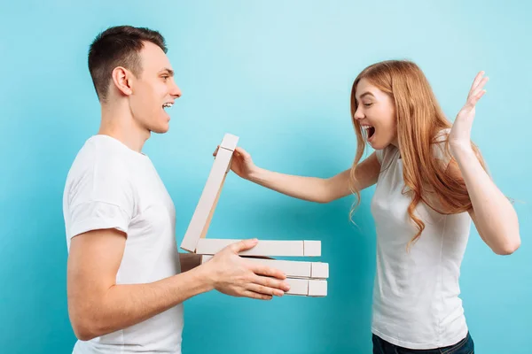 A man brought boxes of Italian pizza to a woman preparing to watch movies on a blue background — Stock Photo, Image