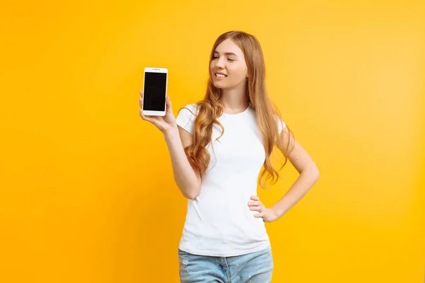 Portret van een mooi meisje, een leeg scherm telefoon waarop een — Stockfoto