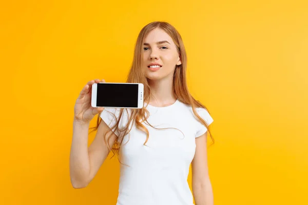 Potret seorang gadis cantik, menunjukkan telepon layar kosong pada — Stok Foto