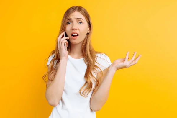 Zirytowany i niepewne dziewczyna rozmawia przez telefon, na żółty b — Zdjęcie stockowe