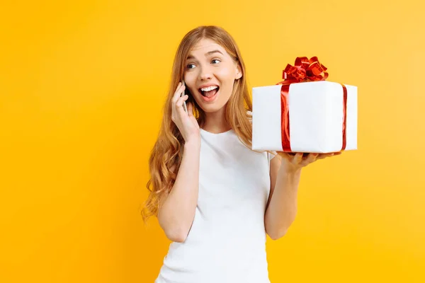 Jovem feliz falando em um telefone celular, mostra uma caixa de presente, o — Fotografia de Stock