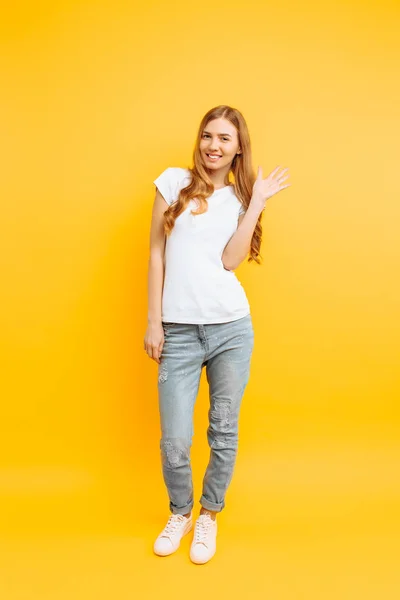 Full length, positive girl, shows a greeting gesture, on a yello — Stock Photo, Image