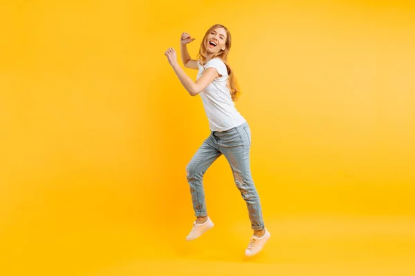 Portret van een vrolijke enthousiaste meisje in een witte T-shirt-stap-springen — Stockfoto