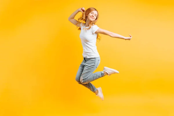 Portret van een vrolijke enthousiaste meisje in een witte T-shirt-stap-springen — Stockfoto