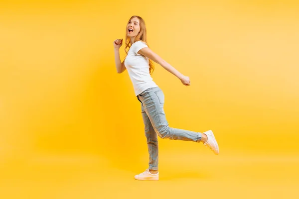 Volledige lengte, positieve meisje lopen op een gele achtergrond. — Stockfoto