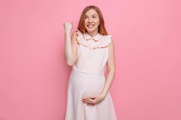 Feliz mujer embarazada se regocija y sostiene el vientre, mostrando el gesto — Foto de Stock