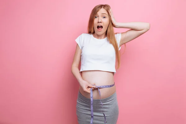 Σοκαρισμένος έγκυος γυναίκα μετρά τη μεγάλη κοιλιά της με τη βοήθεια ενός μέτρου ταινία — Φωτογραφία Αρχείου