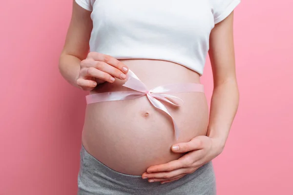 孕妇腹部系上粉红色丝带的照片 — 图库照片