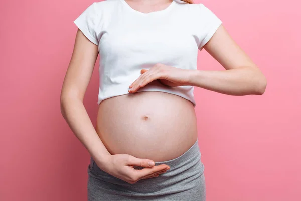 Aşkla göbeği tutan hamile kadın, üçüncü üç aylık dönem — Stok fotoğraf