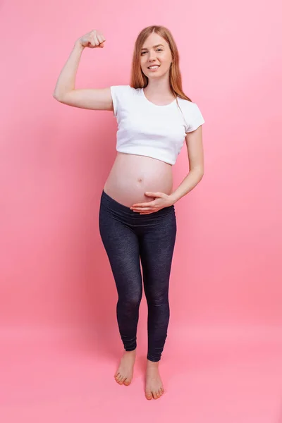 Atletyczna dziewczyna w ciąży pokazuje gest siły — Zdjęcie stockowe