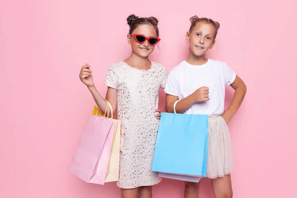 Dos adolescentes sonrientes sostienen bolsas en sus manos después de un viaje de compras —  Fotos de Stock