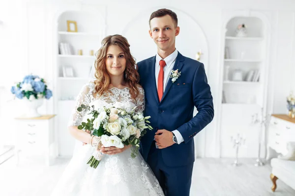 Bela noiva em vestido branco e noivo em terno, posando em interior estúdio branco, casamento — Fotografia de Stock