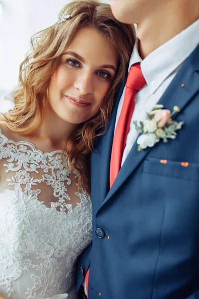 Όμορφη νύφη σε λευκό φόρεμα και ο γαμπρός στο κοστούμι, ποζάρει σε λευκό στούντιο εσωτερικό, γάμος — Φωτογραφία Αρχείου